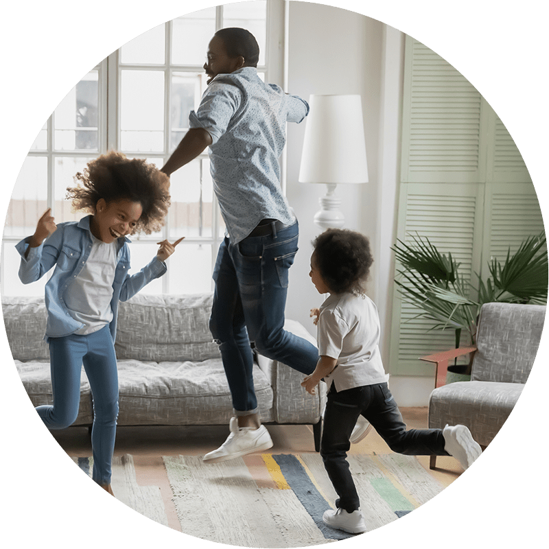 Dad and two children dancing and having fun in their living room. 