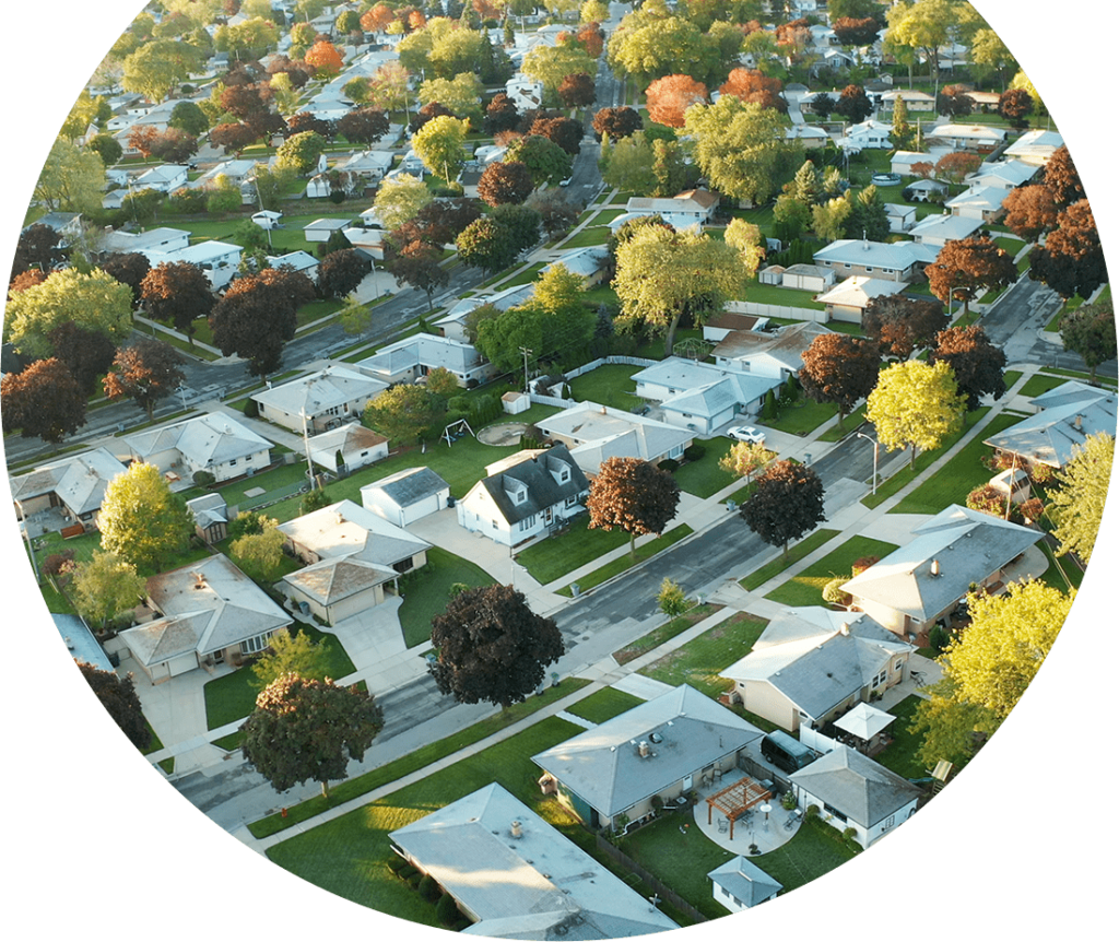 Overview of cityscape showing a neighborhood with many houses. Image is in the shape of a circle. 