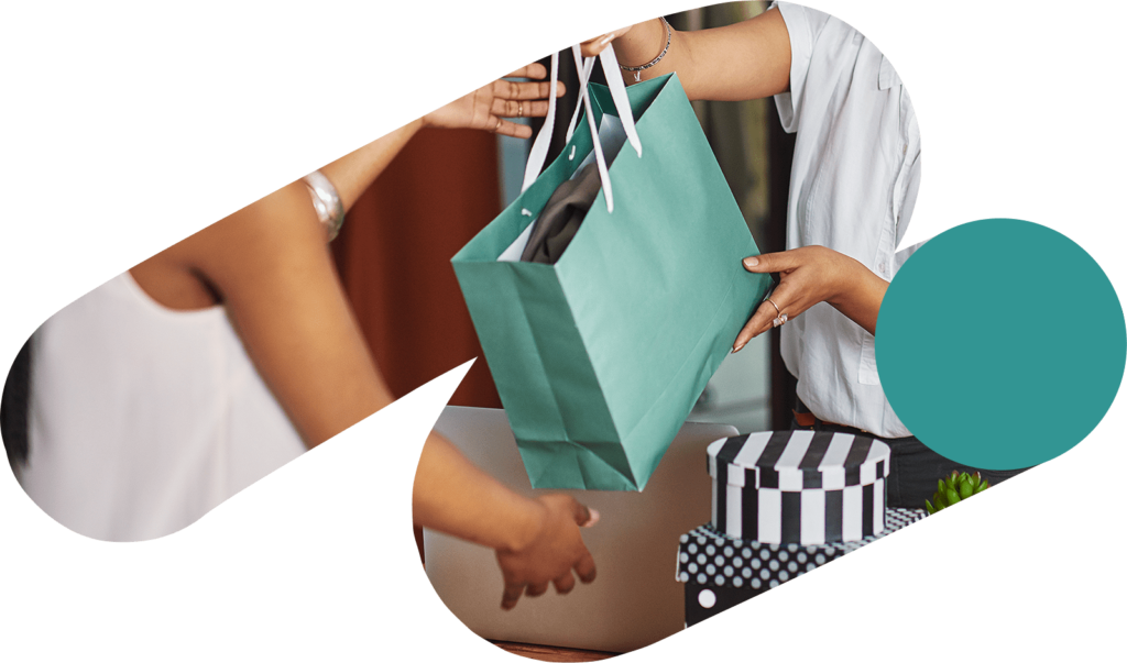 A woman handing another person a teal-colored shopping bag. Photo is inside of a swish shape.