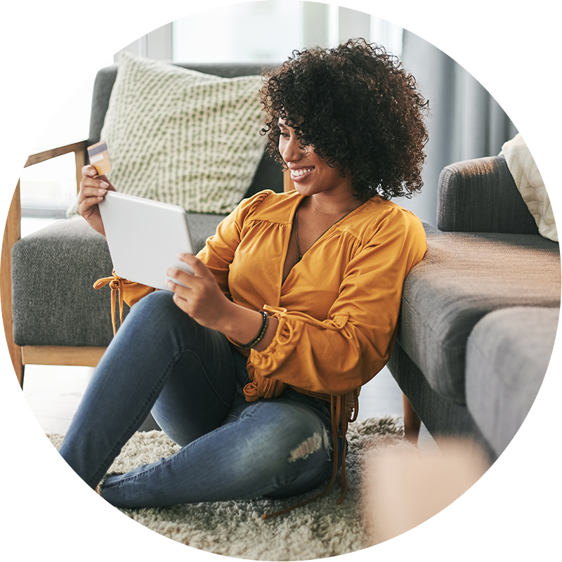 Woman looking at Ipad while sitting on the floor of her living room. Image is in a circle shape.
