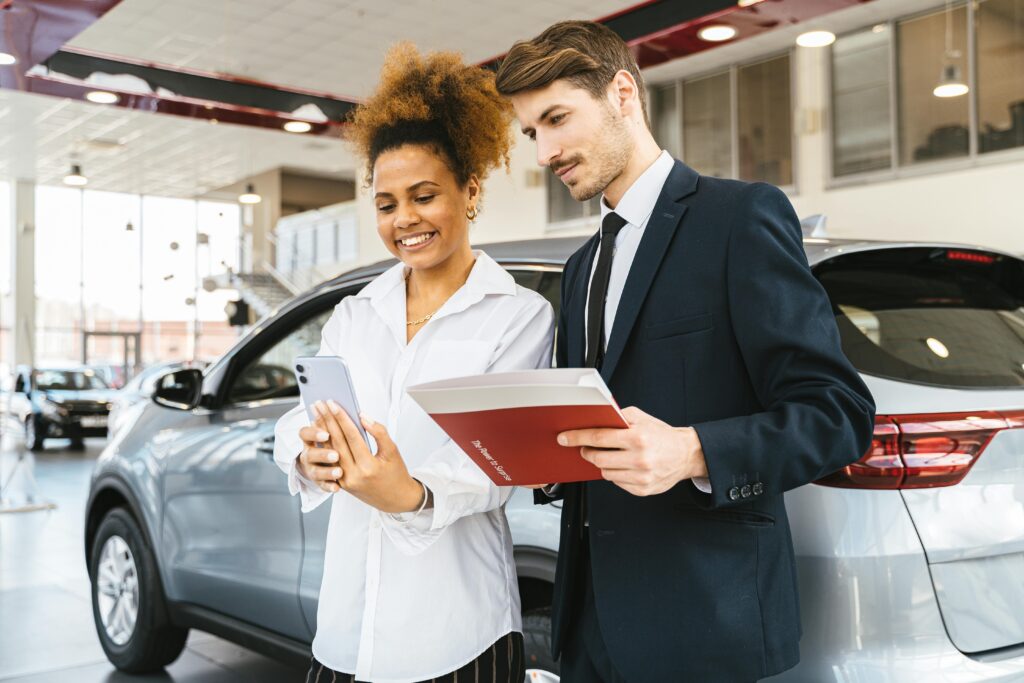 An African-American woman talking to a car salesman in a suit