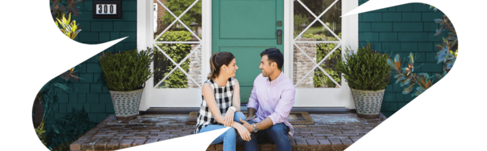 Young couple smiling at each other while sitting on the front porch of their home.