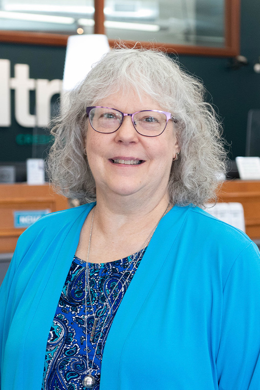 Karen Neel, Member Experience Manager at Alltru Credit Union, pictured inside of the Alltru Downtown Branch wearing a blue cardigan