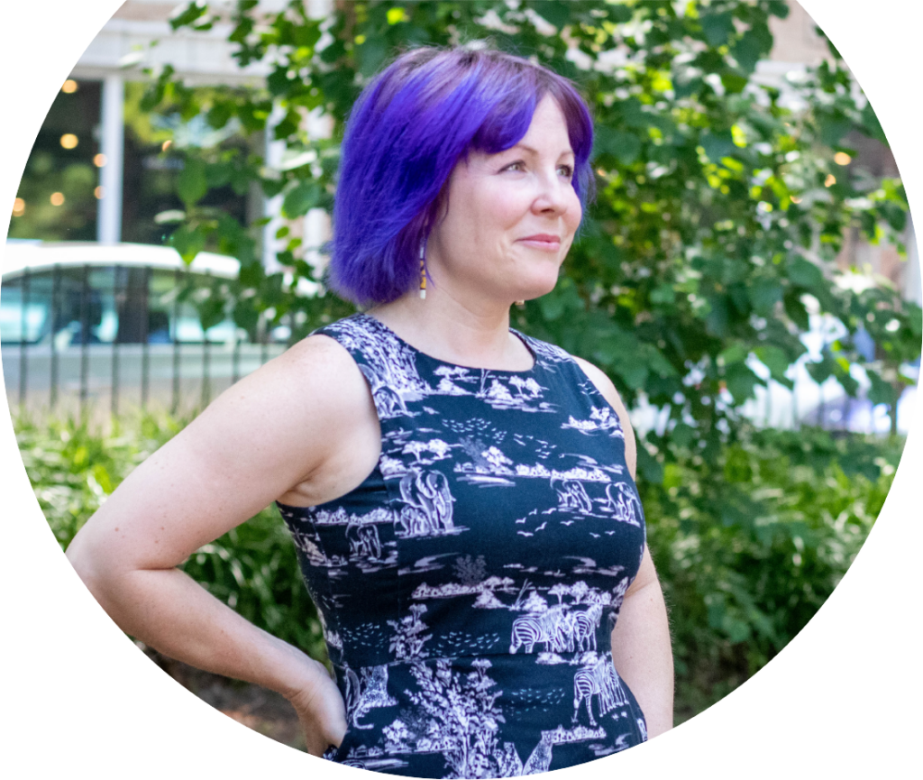 Female Alltru member with purple hair proudly standing with her hand on one hip.