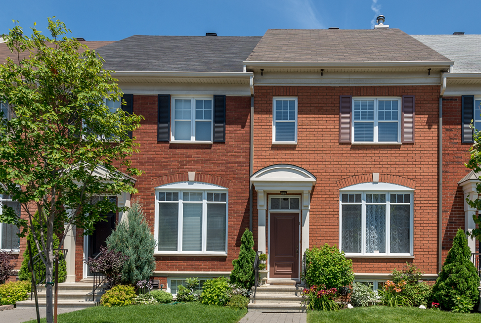 The exterior of two red brick townhomes with brown front doors