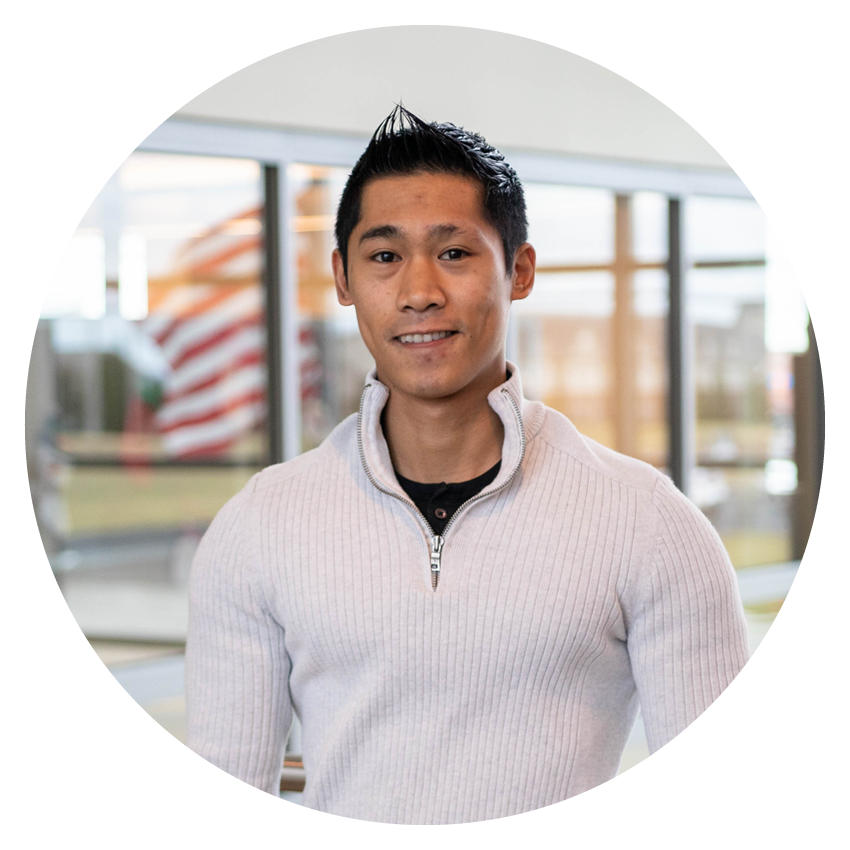 Alltru member Bradley in a tan quarter zip sweater smiling inside an Alltru branch