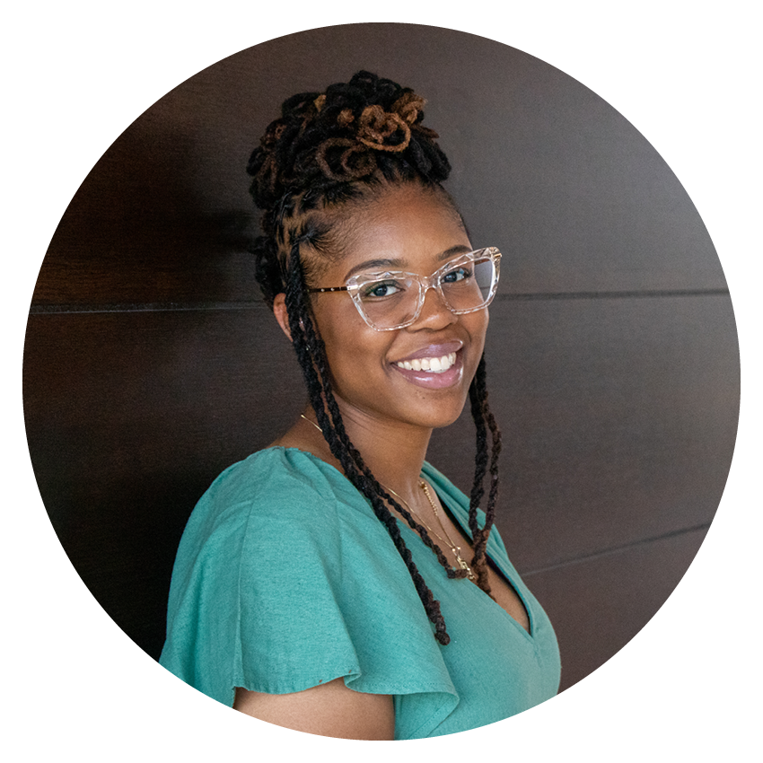 Alltru member Shanese in a teal dress leaning against the wall and smiling inside the Wentzville Alltru branch